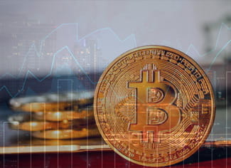 Una moneta Bitcoin con grafici finanziari