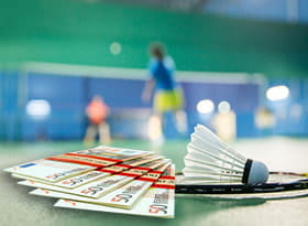 Una racchetta da badminton, un volano, dei soldi e un campo da gioco sullo sfondo