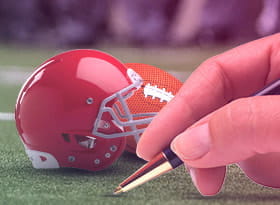 Un casco e un pallone da football americano e una mano con una penna