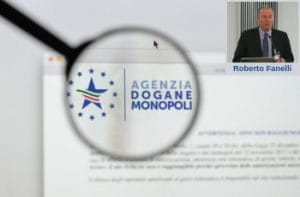 Una lente d’ingrandimento sul logo dell’Agenzia delle Dogane e dei Monopoli e la foto di Roberto Fanelli