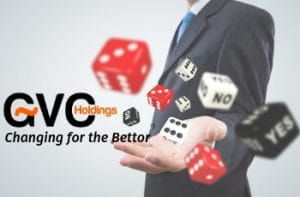 Un uomo in giacca e cravatta lancia dei dadi da gioco dalla mano sinistra, con il logo di GVC Holdings e quello di Changing for the Bettor