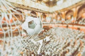 Un pallone da calcio che entra in rete e, sullo sfondo, l'aula della Camera dei Deputati al Parlamento Italiano