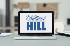 Un computer portatile con il logo di William Hill posato sulla scrivania di un ufficio