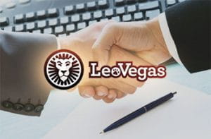 Due mani che si stringono a una scrivania, con un laptop e il logo di LeoVegas