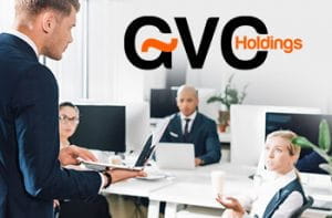 Un gruppo di persone sedute a una scrivania in un ufficio e il logo di GVC