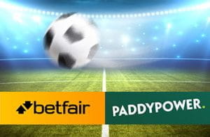 Un pallone da calcio e, sullo sfondo, uno stadio illuminato durante un match notturno, con i loghi di Betfair e Paddy Power