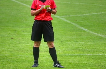 Un arbitro di calcio sanziona con un cartellino giallo