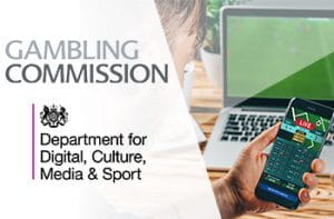 I loghi della UK Gambling Commission e del DCMS, un laptop e uno smartphone collegati ai siti di due bookmaker online