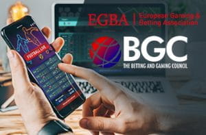 I loghi di EGBA e BGC e uno smartphone collegato a un bookmaker online