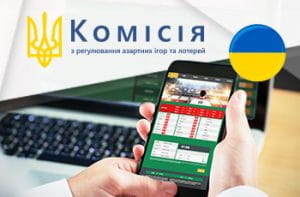 Il logo della gambling commission ucraina (KRAIL) e uno smartphone collegato al sito di un bookmaker online