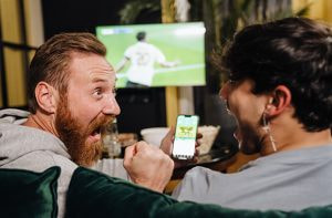Uomini con smartphone davanti a evento sportivo