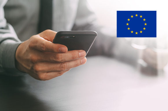 Una persona tiene in mano uno smartphone, logo dell’Unione Europea