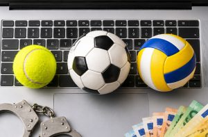 Pallina da tennis, palloni da calcio e pallavolo, manette e banconote su una tastiera